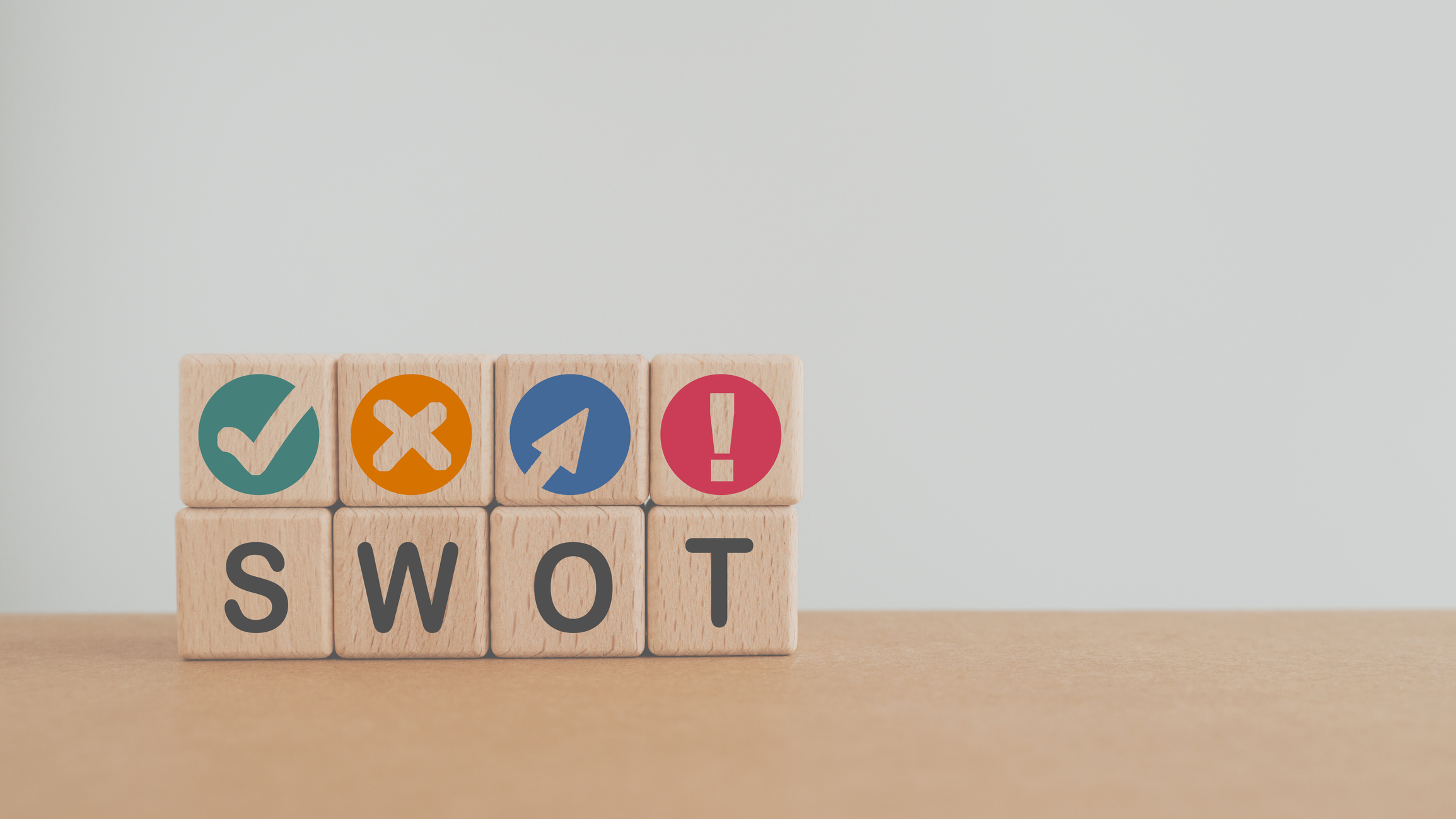 quatro cubos de madeira formam a sigla SWOT, e acima de cada um deles, mais 4 cubos tem símbolos de cada termo correspondente do SWOT.