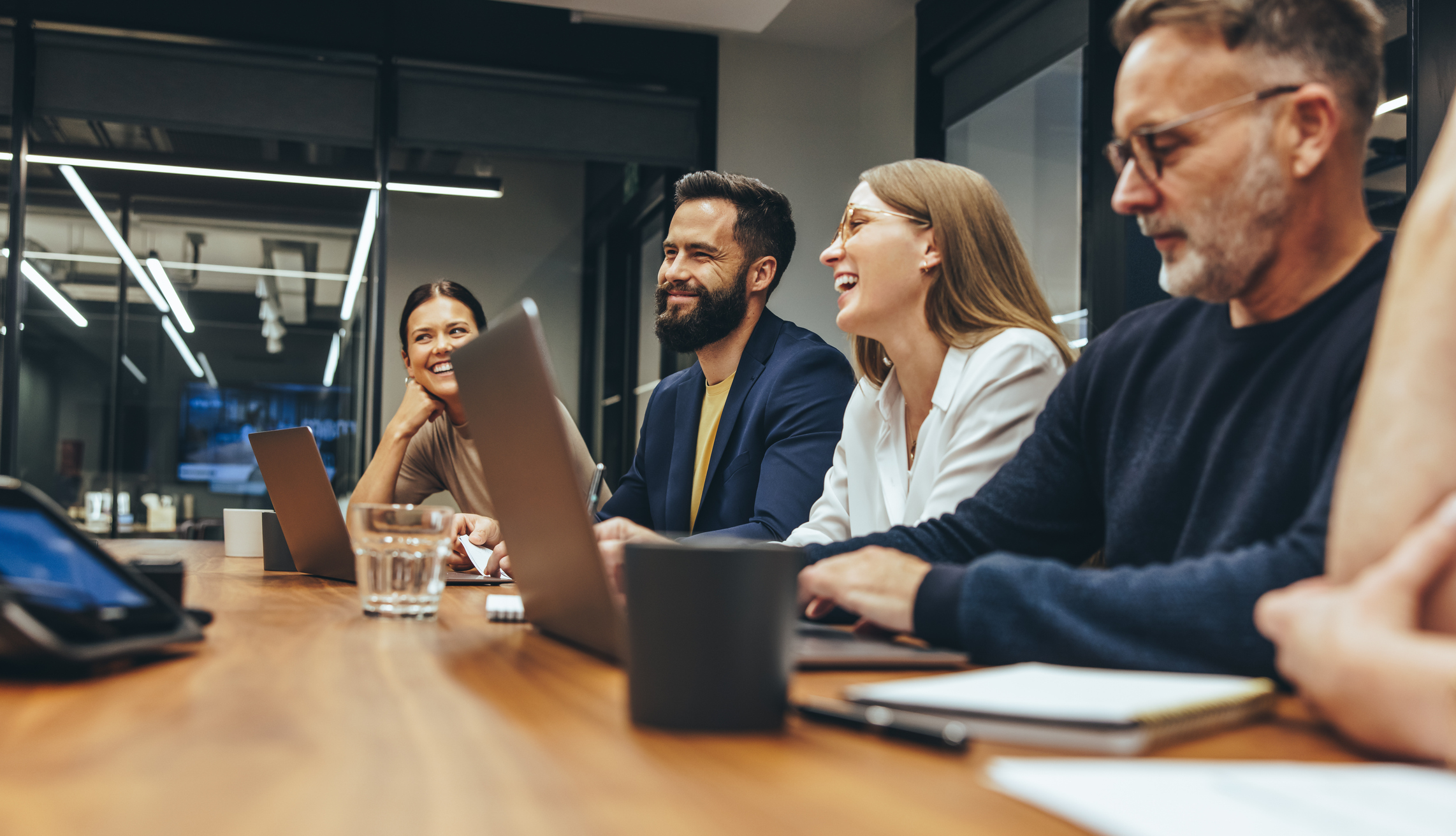 Pessoas felizes em mesa de trabalho fazem reunião.